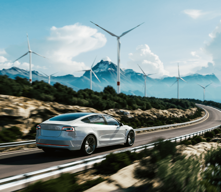 Voiture qui roule sur une route avec des éoliennes derrière et une belle chaîne de montagnes !